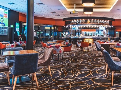 The Great Western Lounge: armchairs around tables, the curved bar and a big-screen TV